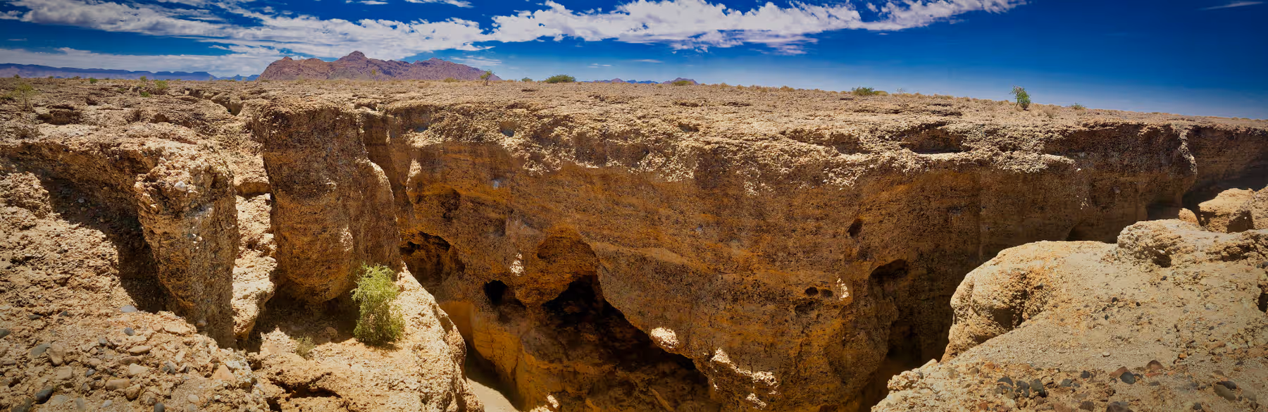 Panoramisch uitzicht op rotsachtig canyonlandschap onder een partly bewolkte blauwe hemel.