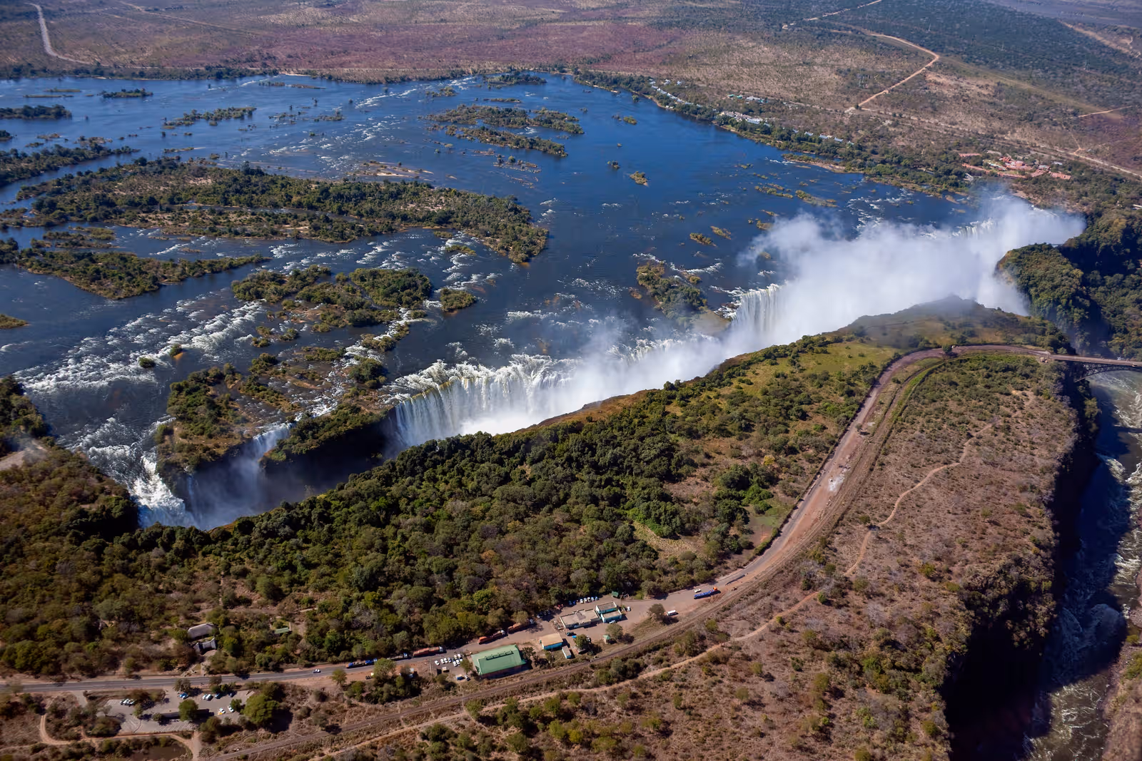 Luchtfoto van de Victoriawatervallen met ruisende watervallen omgeven door groen en rivieren in een ruig landschap.