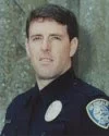 Portrait of a male police officer in uniform with a badge on his shoulder.