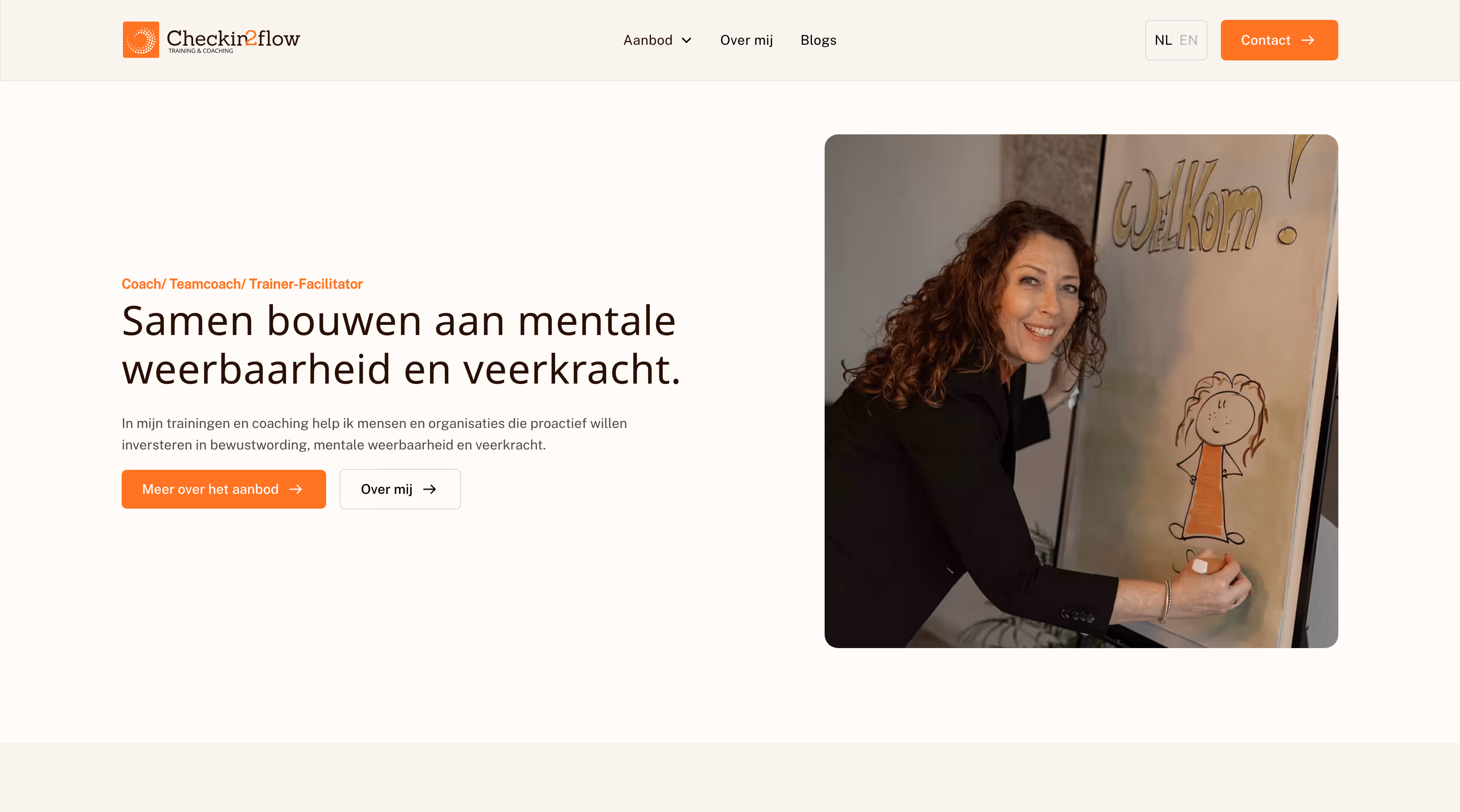 Vrouw die op bord schrijft met welkom en een poppetje, glimlachend naar camera.
