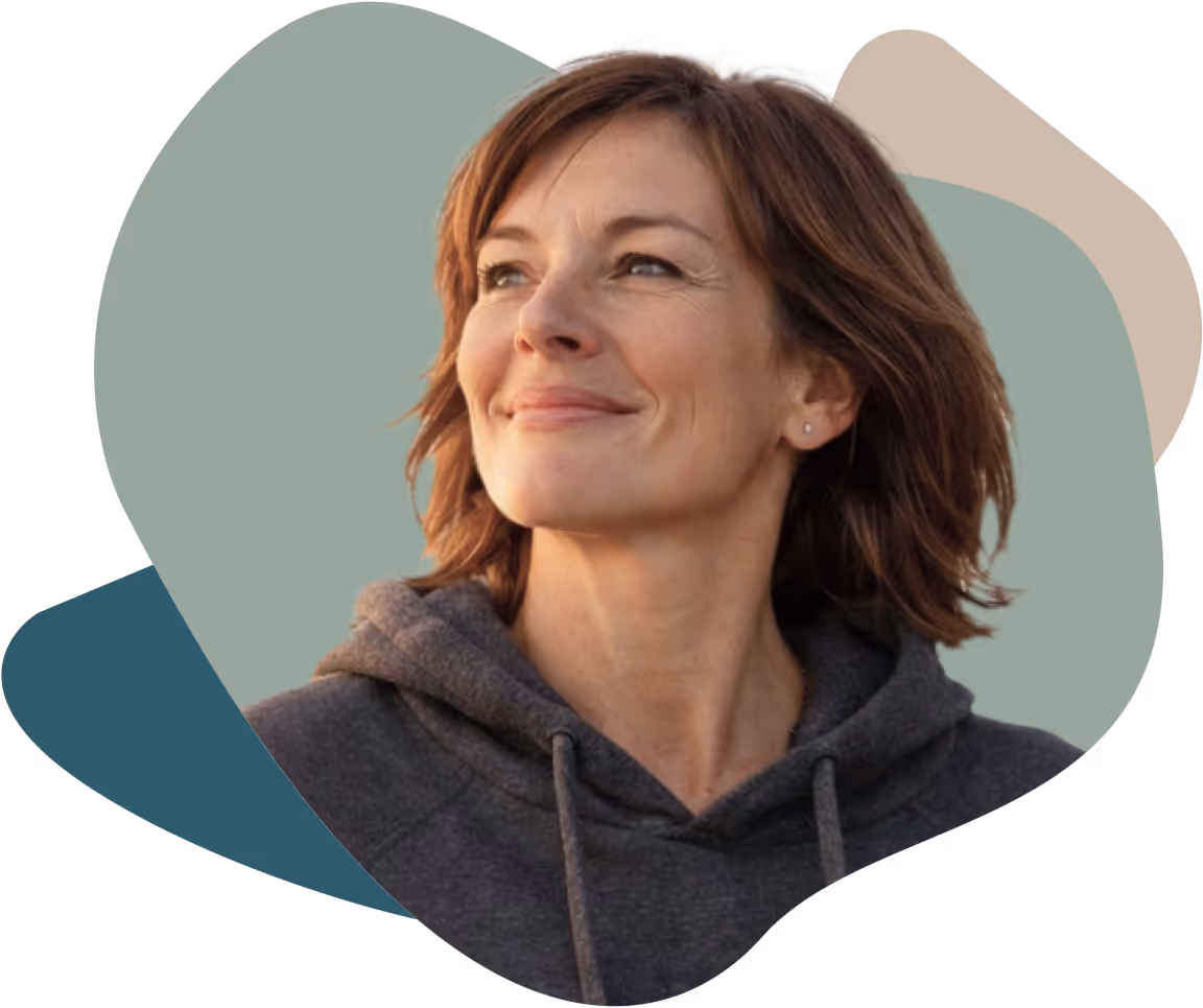 Smiling woman with short brown hair wearing a gray hoodie looking to the side against a layered abstract color background.