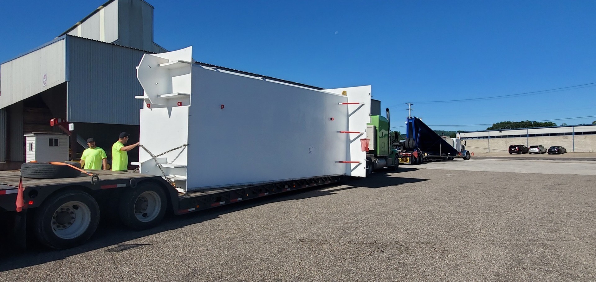 White plant module on a lowboy trailer leaving the terminal