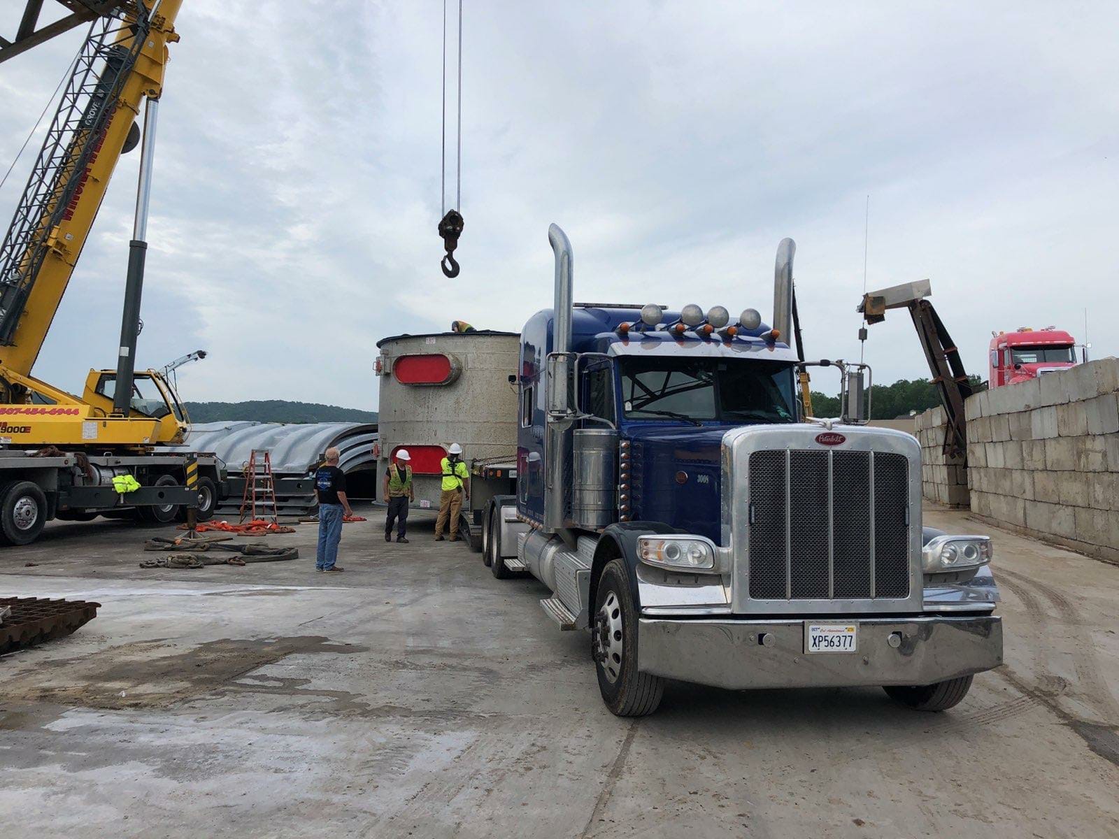 Crane lifting an oversized steel structure onto a trailer