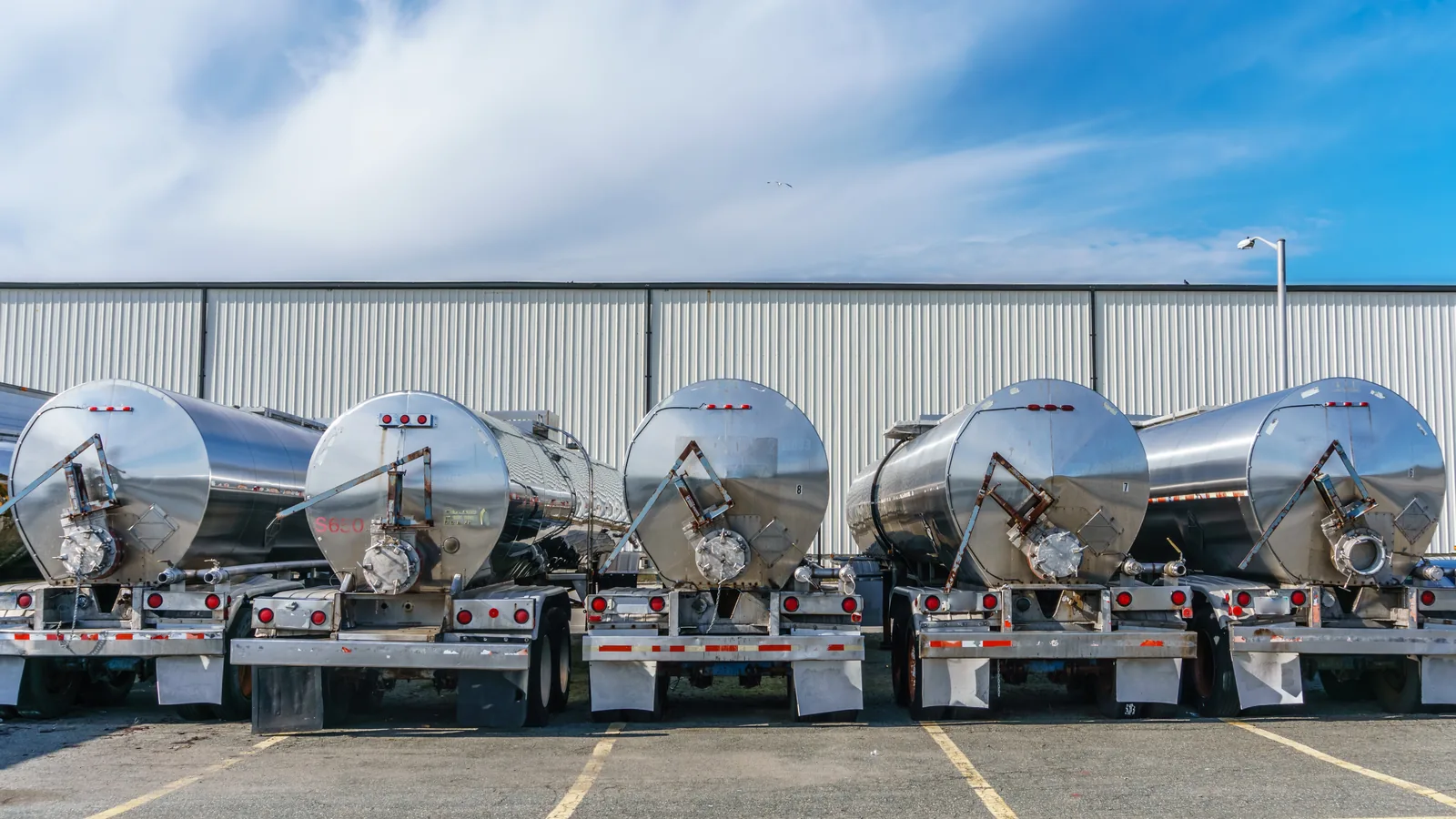 Row of stainless steel tank trailers parked at a carrier yard