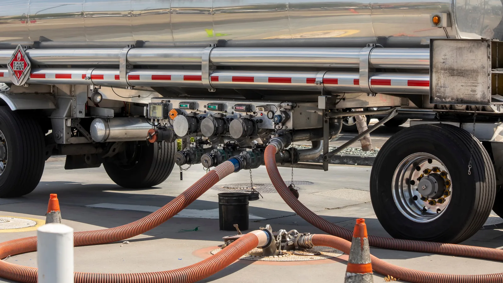 Stainless steel tank trailer with transfer hoses connected at a loading rack