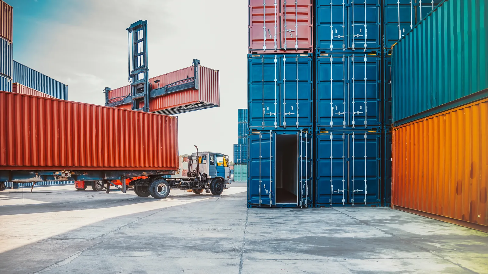 Reach stacker lifting a container onto a chassis in a stacked container yard
