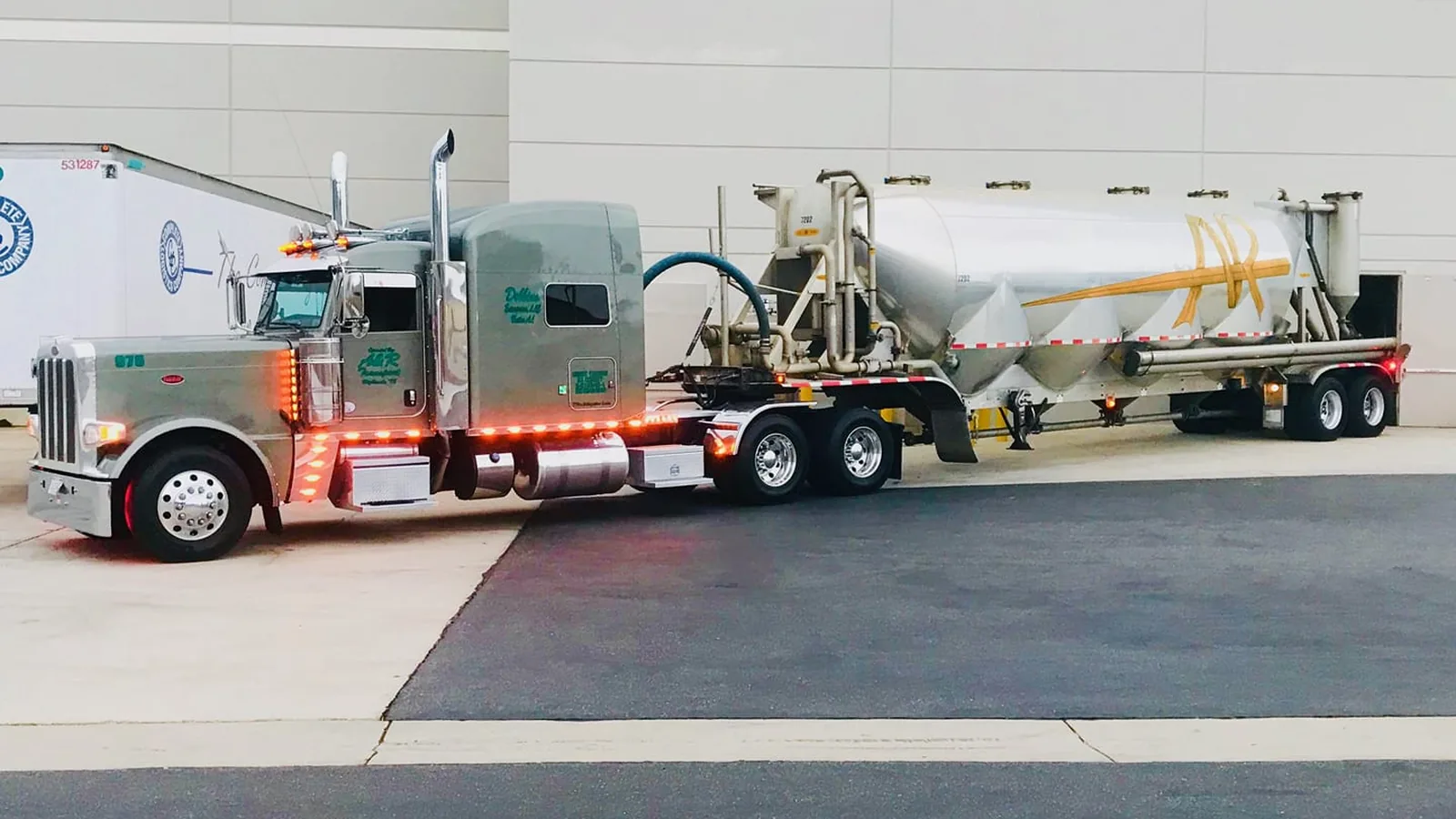 Pneumatic dry bulk trailer with tractor parked at a plant