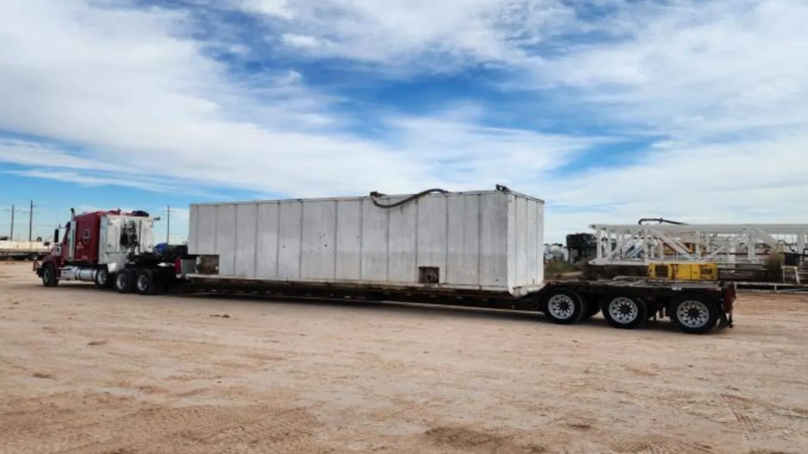 White ISO tank container on a flatbed trailer in an industrial yard, the reusable equipment side of the comparison