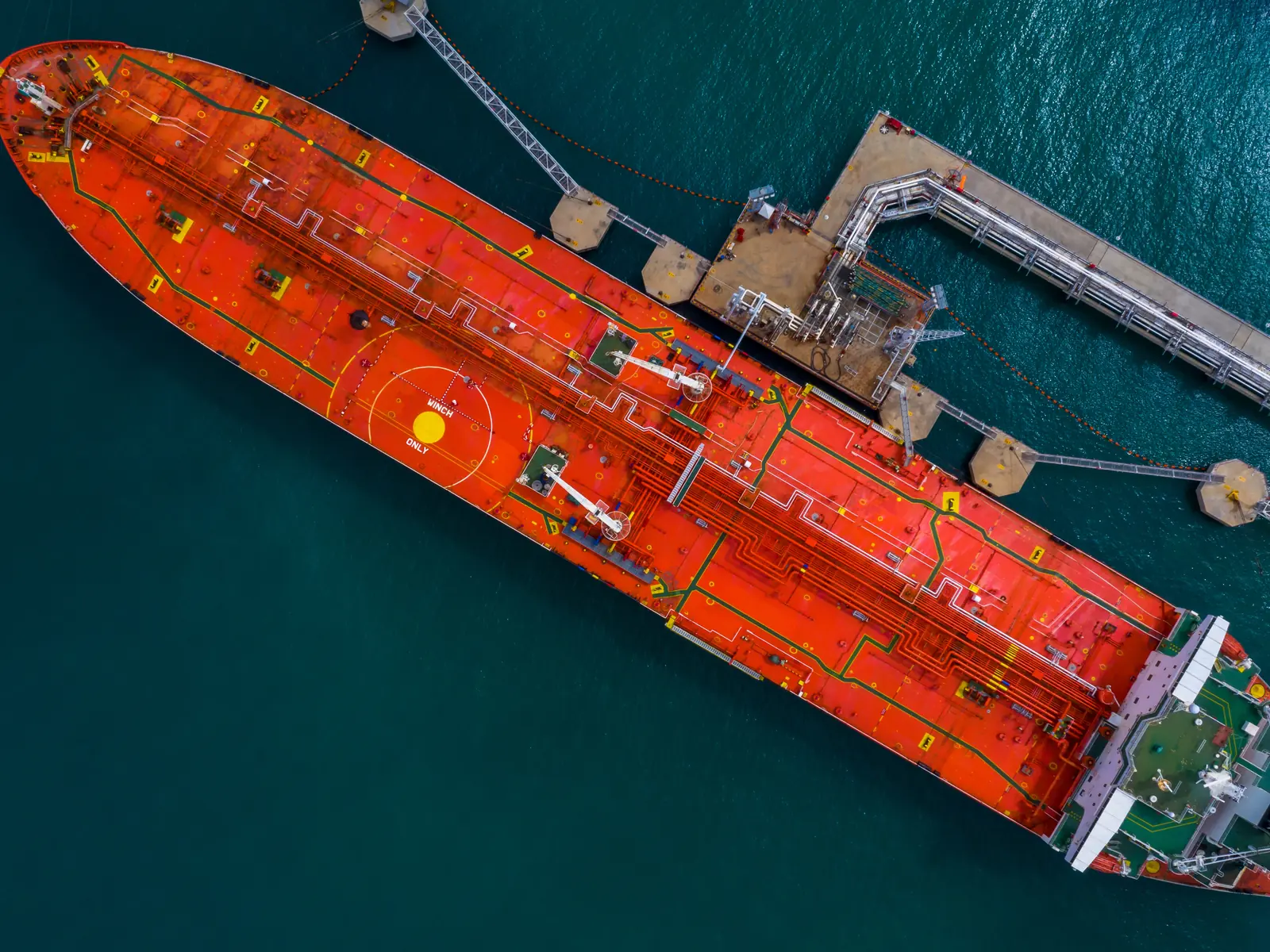 Aerial view of an oil tanker alongside a jetty with loading arms connected