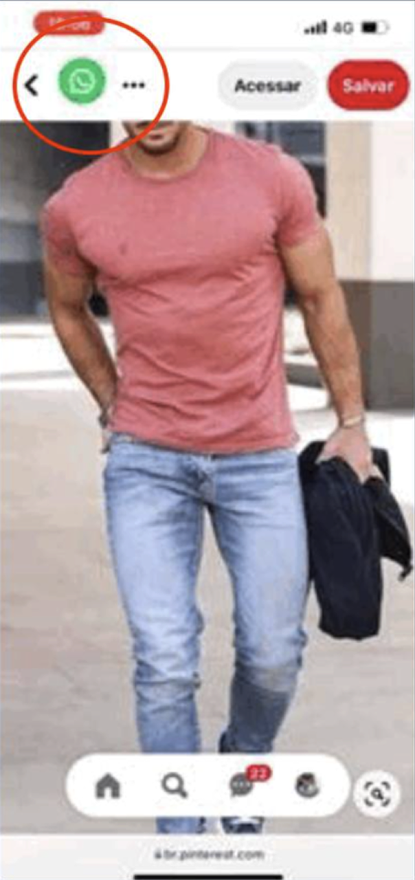 Man wearing a fitted pink t-shirt and light blue jeans walking outdoors, holding a black jacket in his left hand.