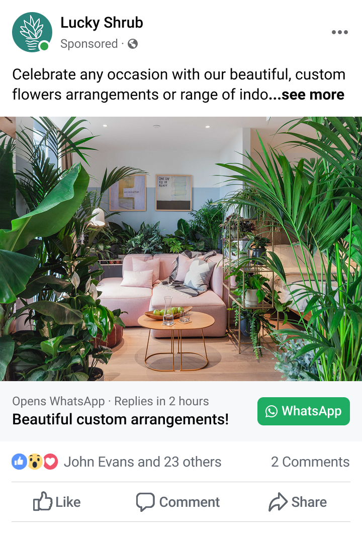 Indoor living room with a pink sectional sofa, wooden coffee table with glasses and fruit, surrounded by lush green plants.