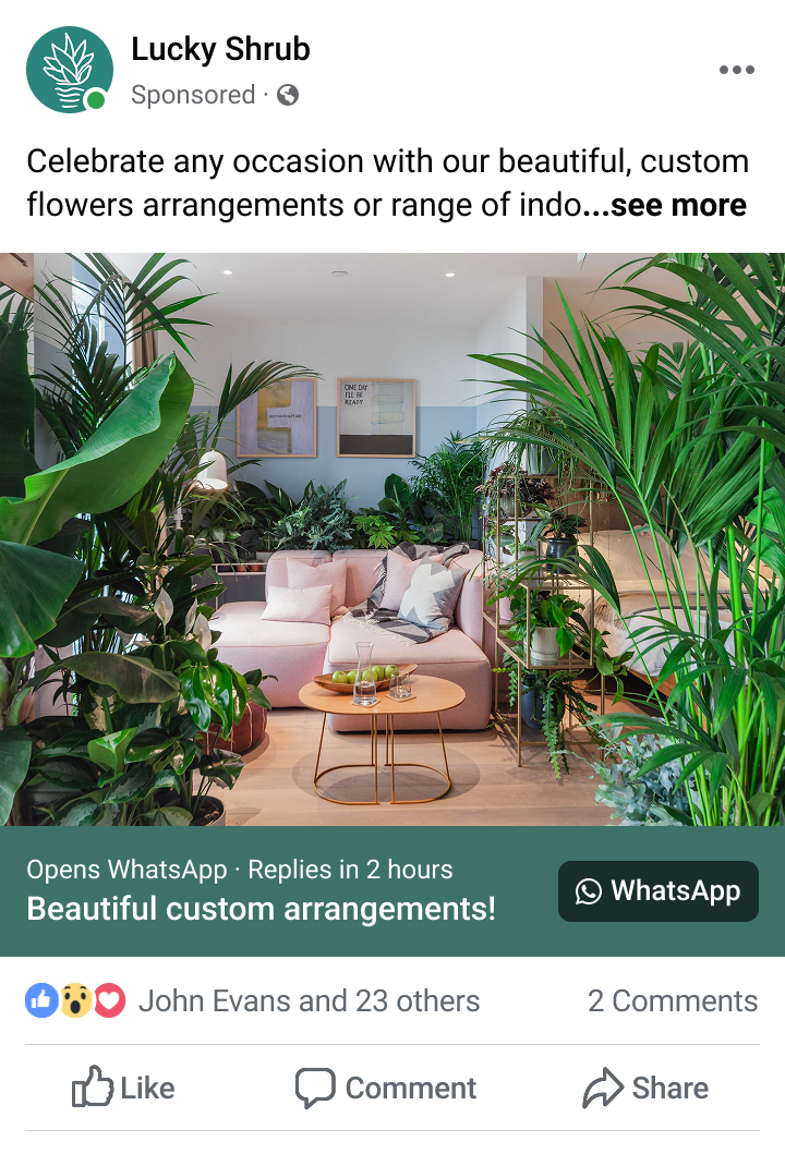 Cozy living room with a pink sectional sofa surrounded by lush green indoor plants and a small round wooden coffee table.