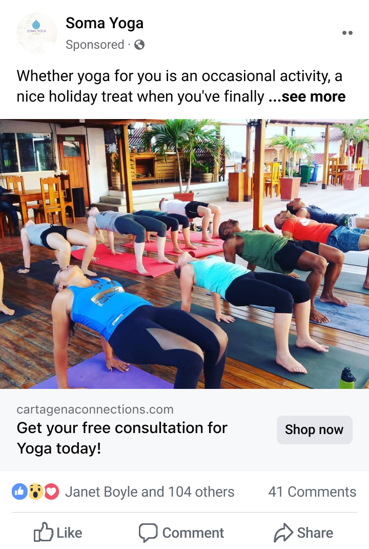 Group of people practicing yoga indoors on mats, performing upward plank pose with palms and feet on the floor.