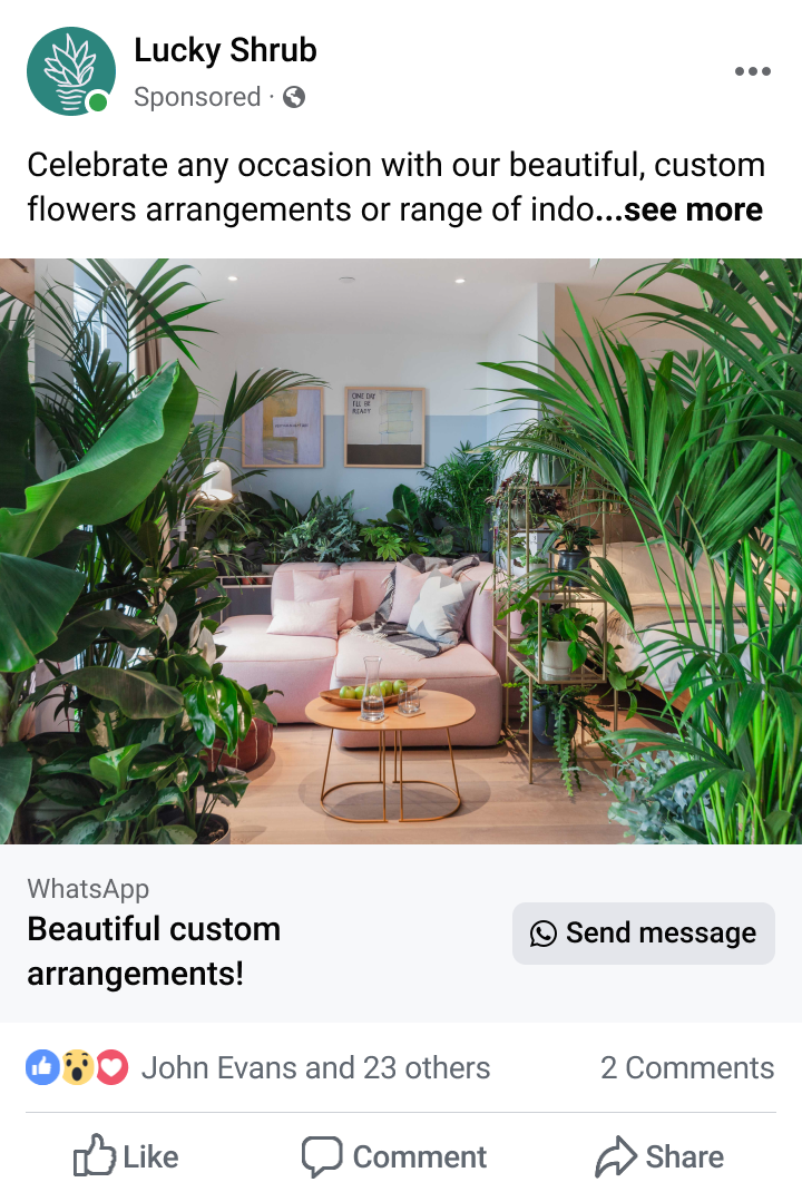 Living room with a pink sectional sofa surrounded by numerous green indoor plants and a small wooden coffee table with glasses and fruit.
