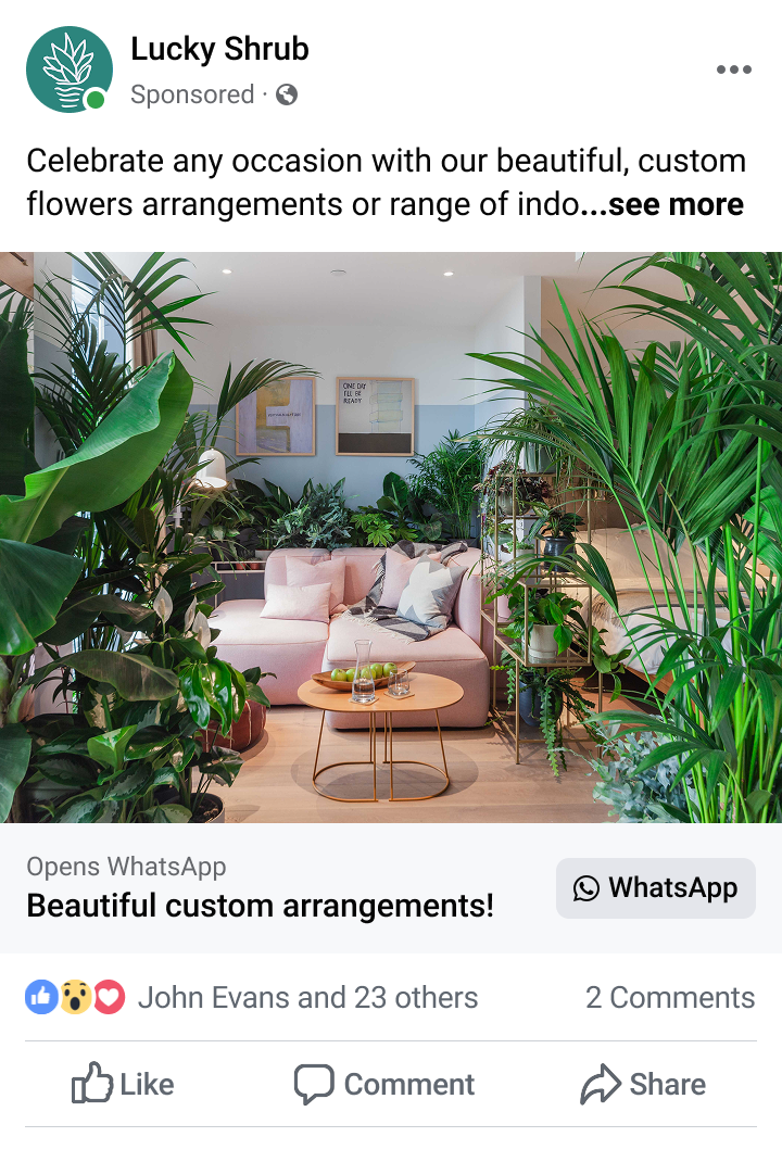 Indoor living room with a pink sofa surrounded by lush green plants and a round wooden coffee table with a glass pitcher and green apples.