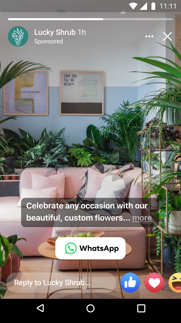 Indoor scene with a pink sofa surrounded by various green potted plants and framed art on a blue and white wall.