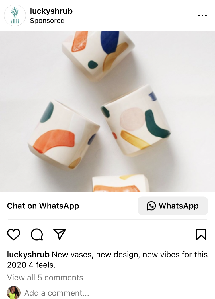 Four small white ceramic vases with colorful abstract shapes in orange, blue, green, and yellow on a white surface.