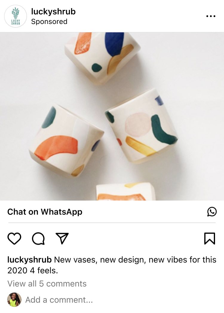Four small white ceramic vases with abstract colorful shapes in orange, blue, green, and yellow on a white surface.