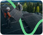 Zwei Arbeiter installieren Solarmodule auf einem Dachdach mit Wald im Hintergrund.