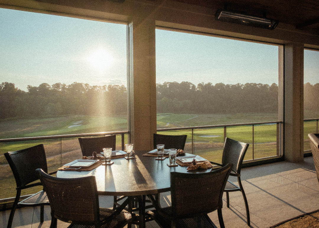 Screened porch dining table overlooking a golf course at sunset