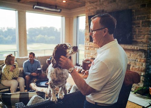Man petting his dog in a screened porch with a stone fireplace