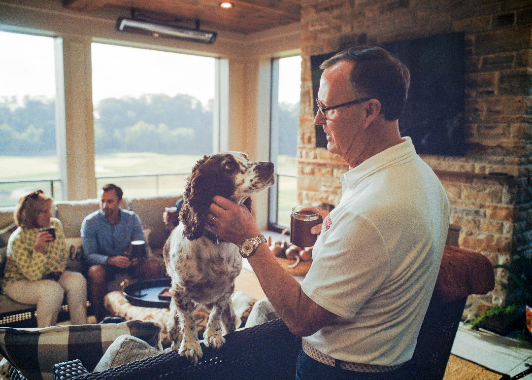 Man petting his dog in a screened porch with a stone fireplace