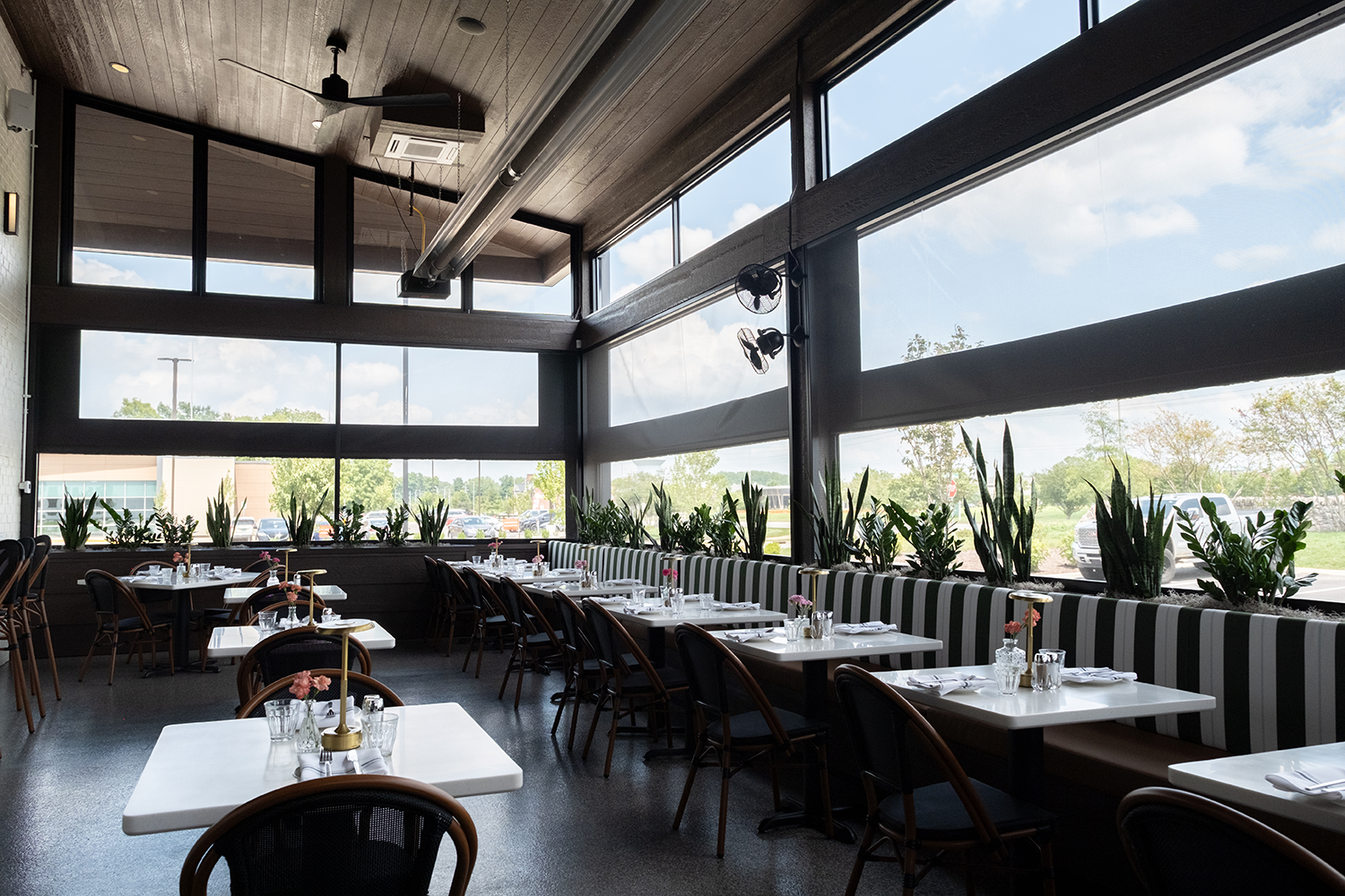 Salento Italia's screened dining room with striped booth seating and floor-to-ceiling glass walls