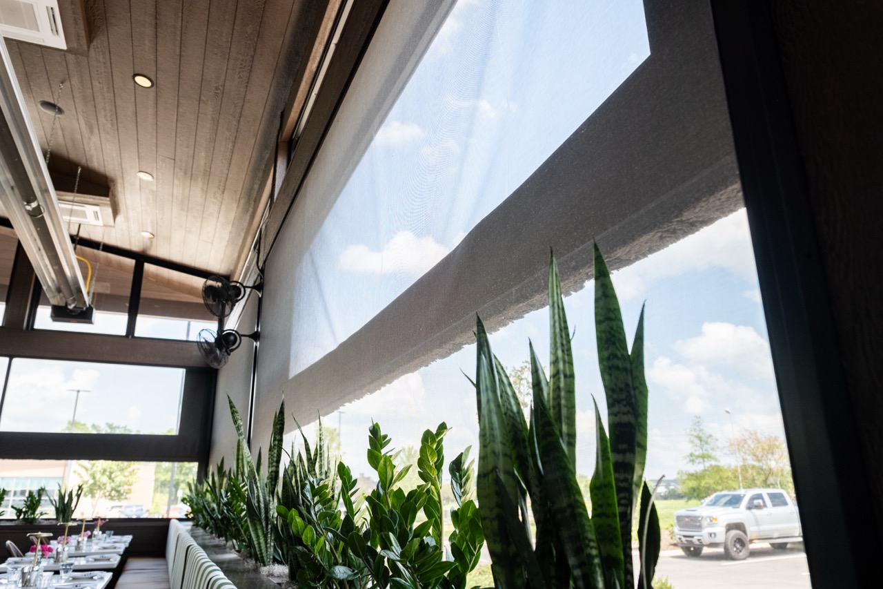 Motorized retractable screen partially lowered over a dining room window at Salento Italia