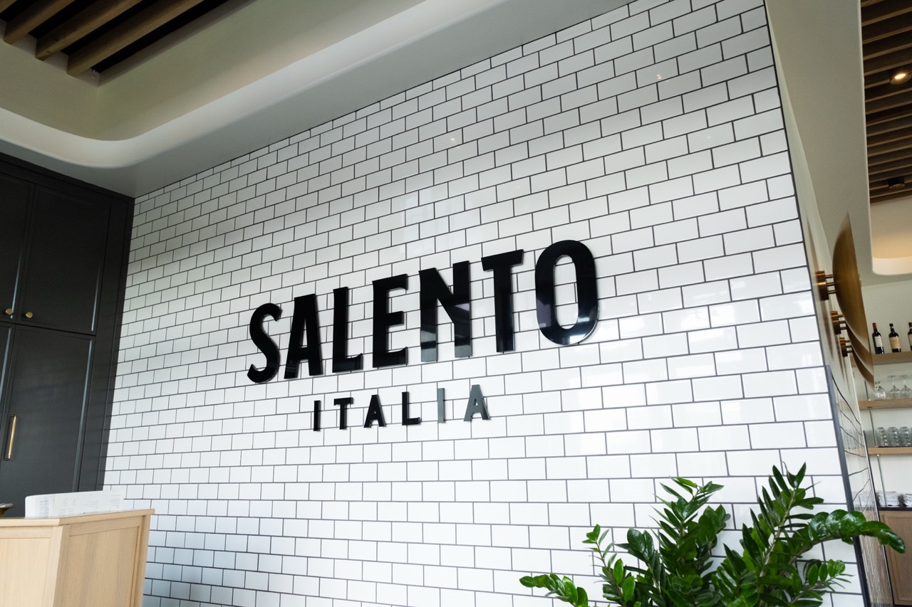 Salento Italia logo sign on a white subway tile wall near the entrance