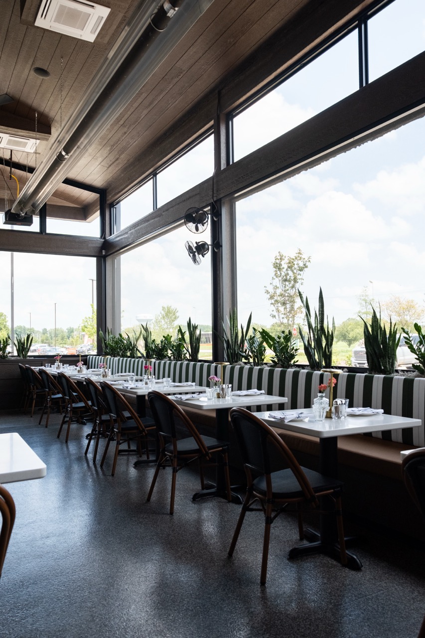 Row of dining booths along a wall of windows with retractable screen tracks at Salento Italia