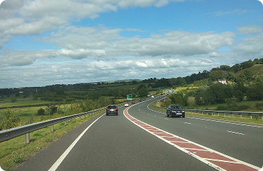 Car on a dual carriageway winding through green countryside