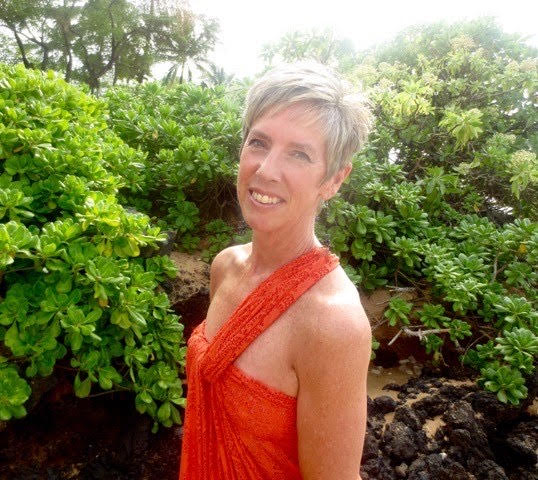 Photo of Founder Dr Dean, wearing a colorfully patterned top in front of a patterned lavender background