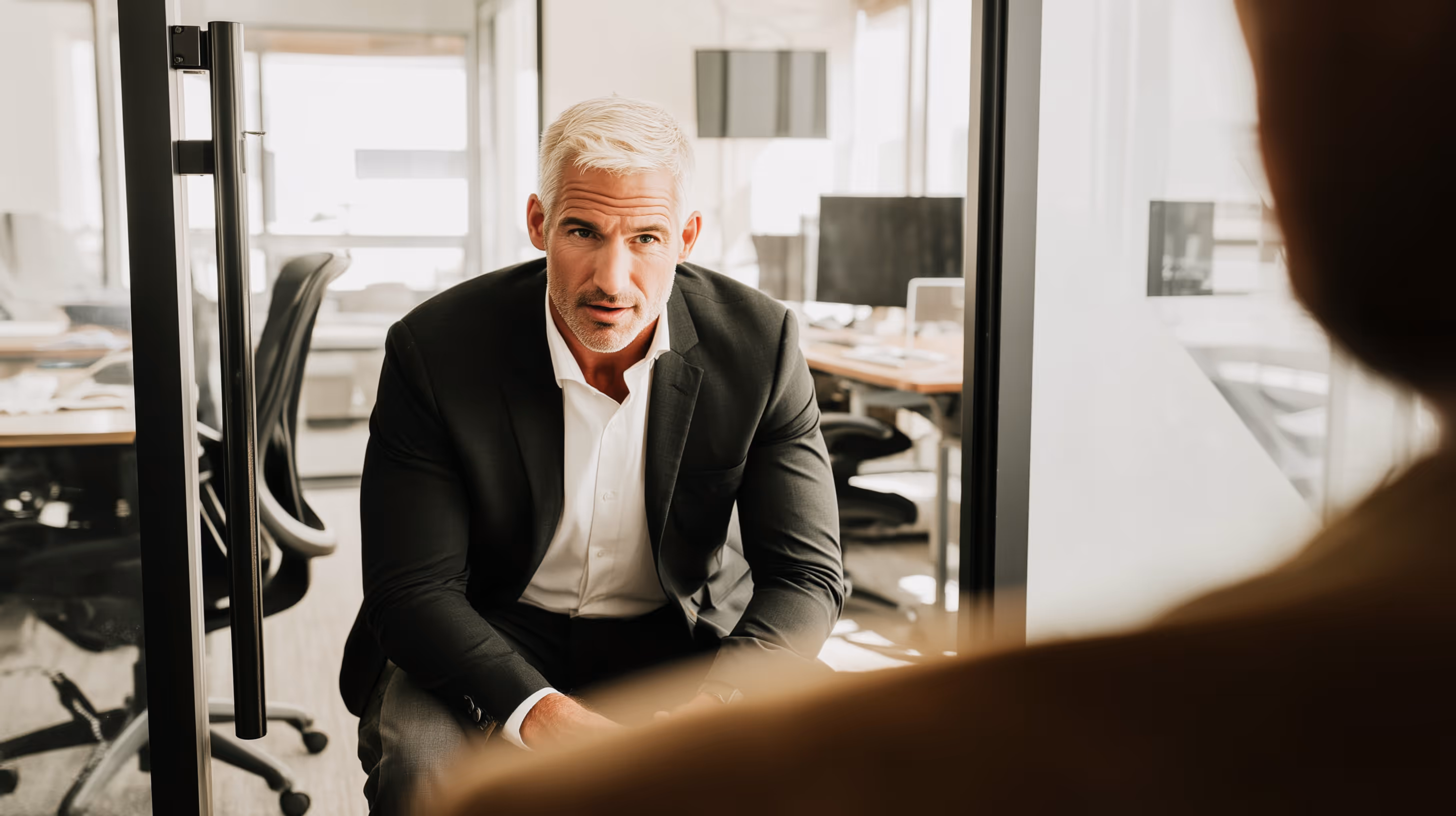 Mature man in a suit attentively listening during a conversation in a modern office.