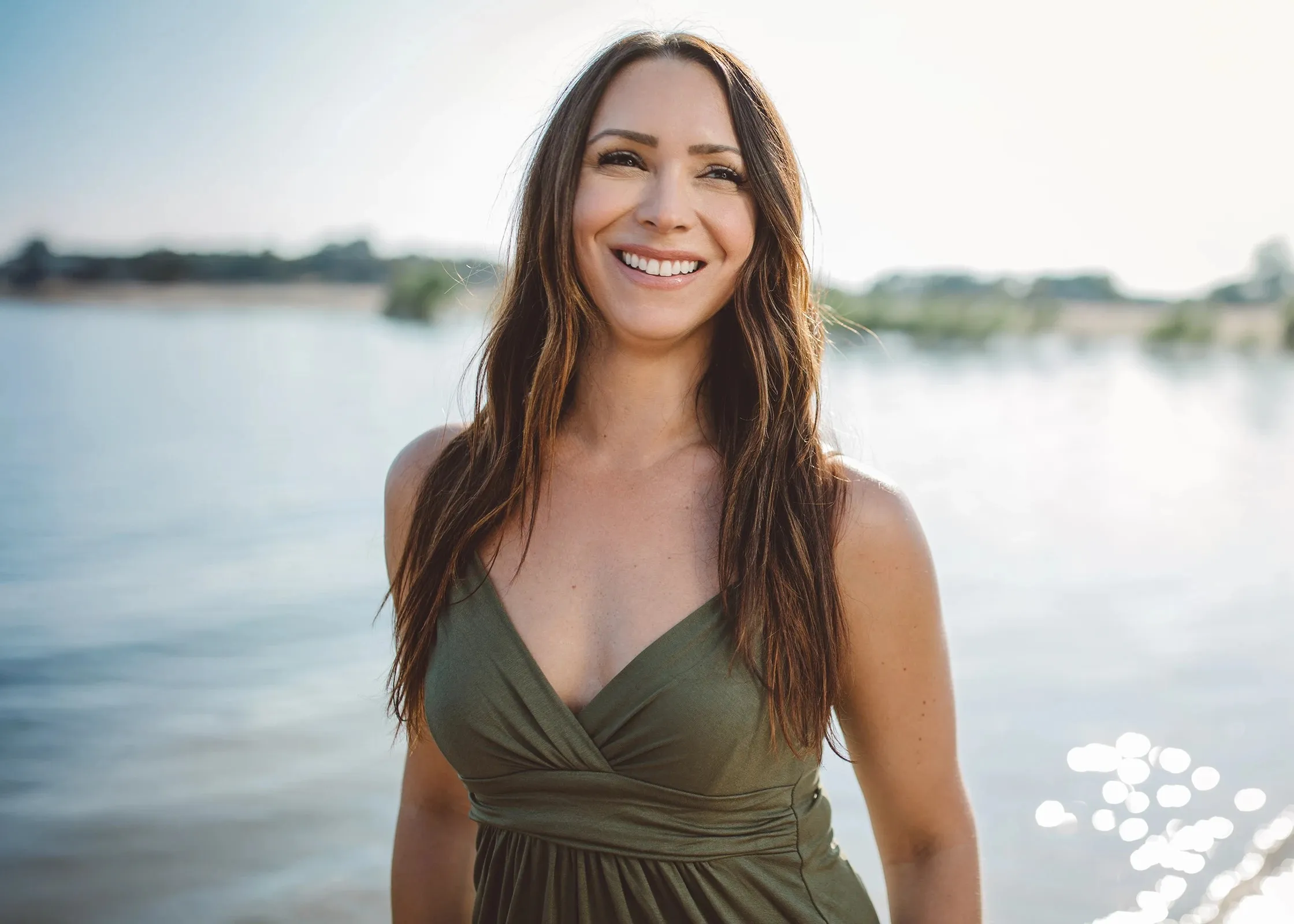 A woman smiling, standing by the beach