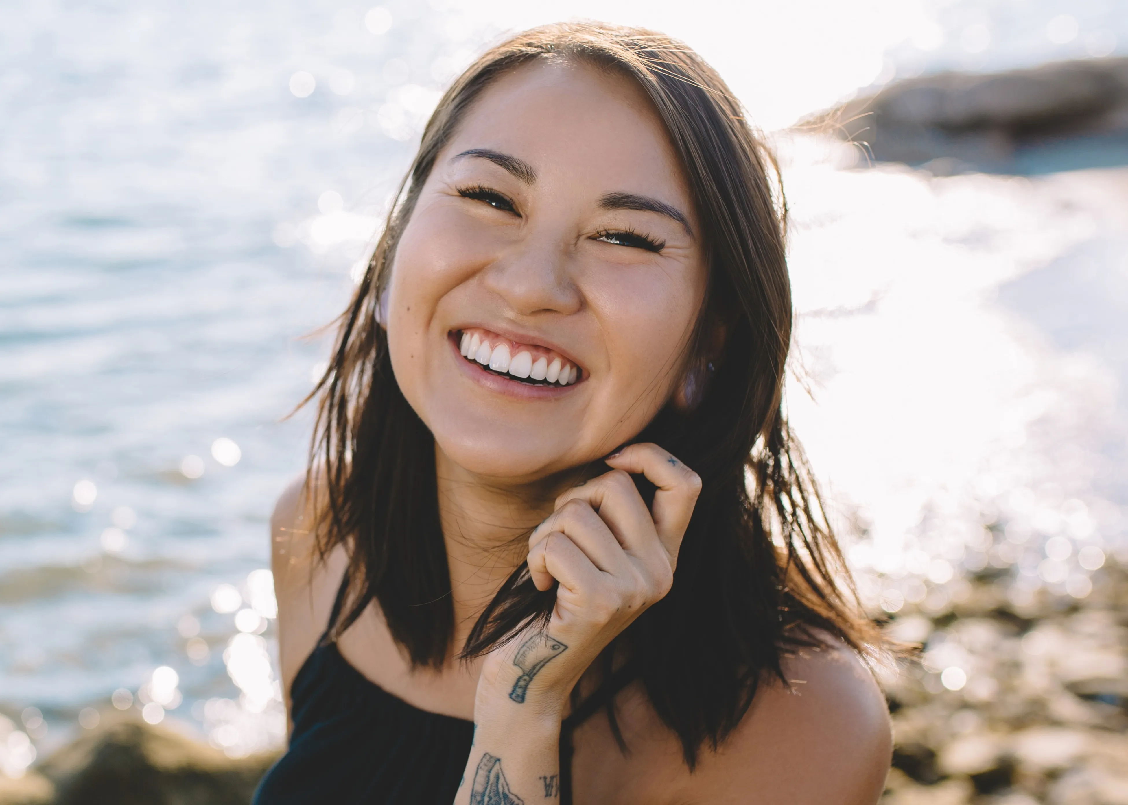 A woman smiles as she stands near the water.