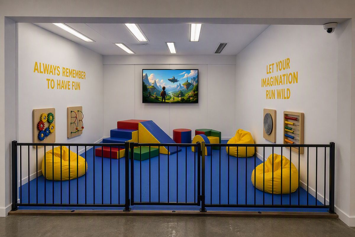 The MFF playroom: soft play shapes, bean bags and a movie screen behind a child safety fence