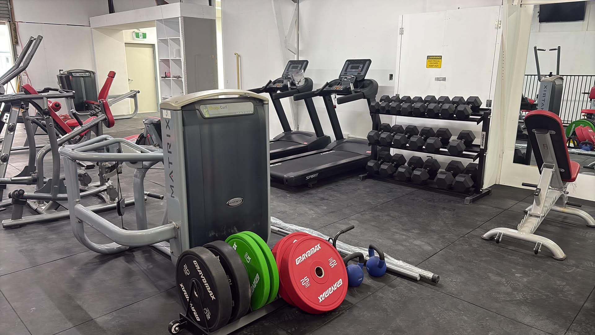 Treadmills, dumbbell rack and bumper plates in the cardio and free weights area