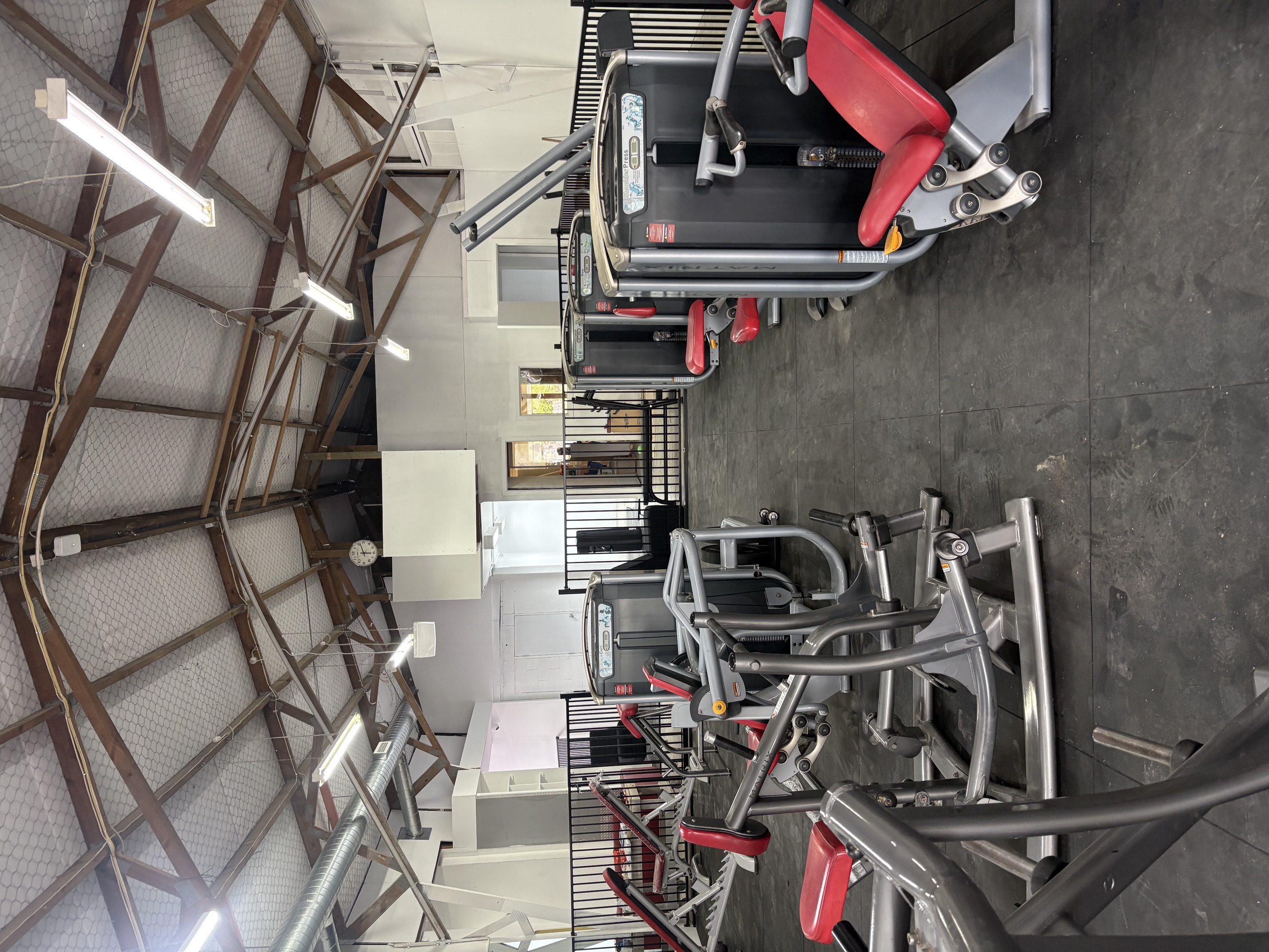 Aisle of Matrix pin-loaded machines including shoulder press and biceps curl
