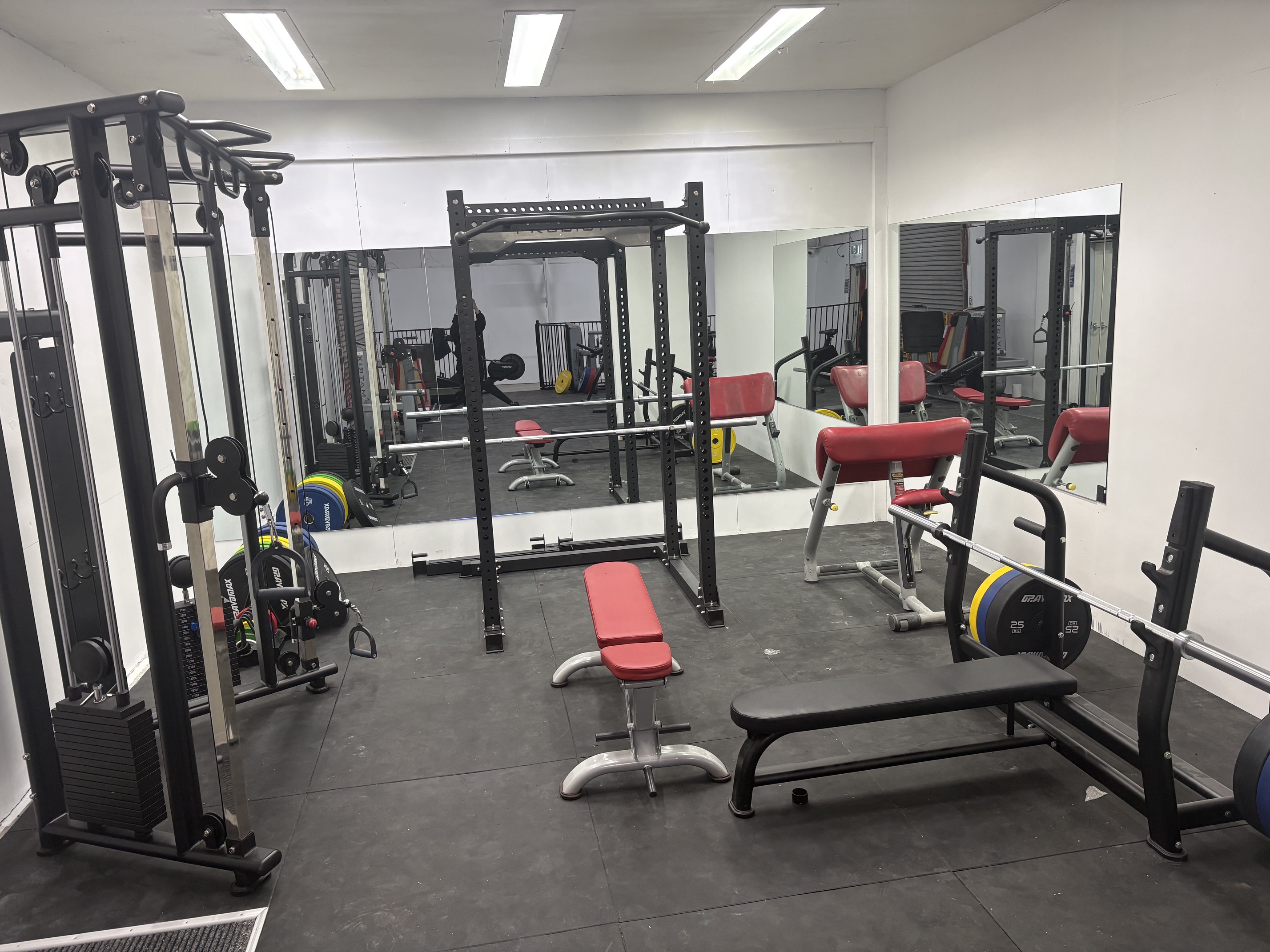 Strength room with power rack, cable crossover, bench press and mirrors