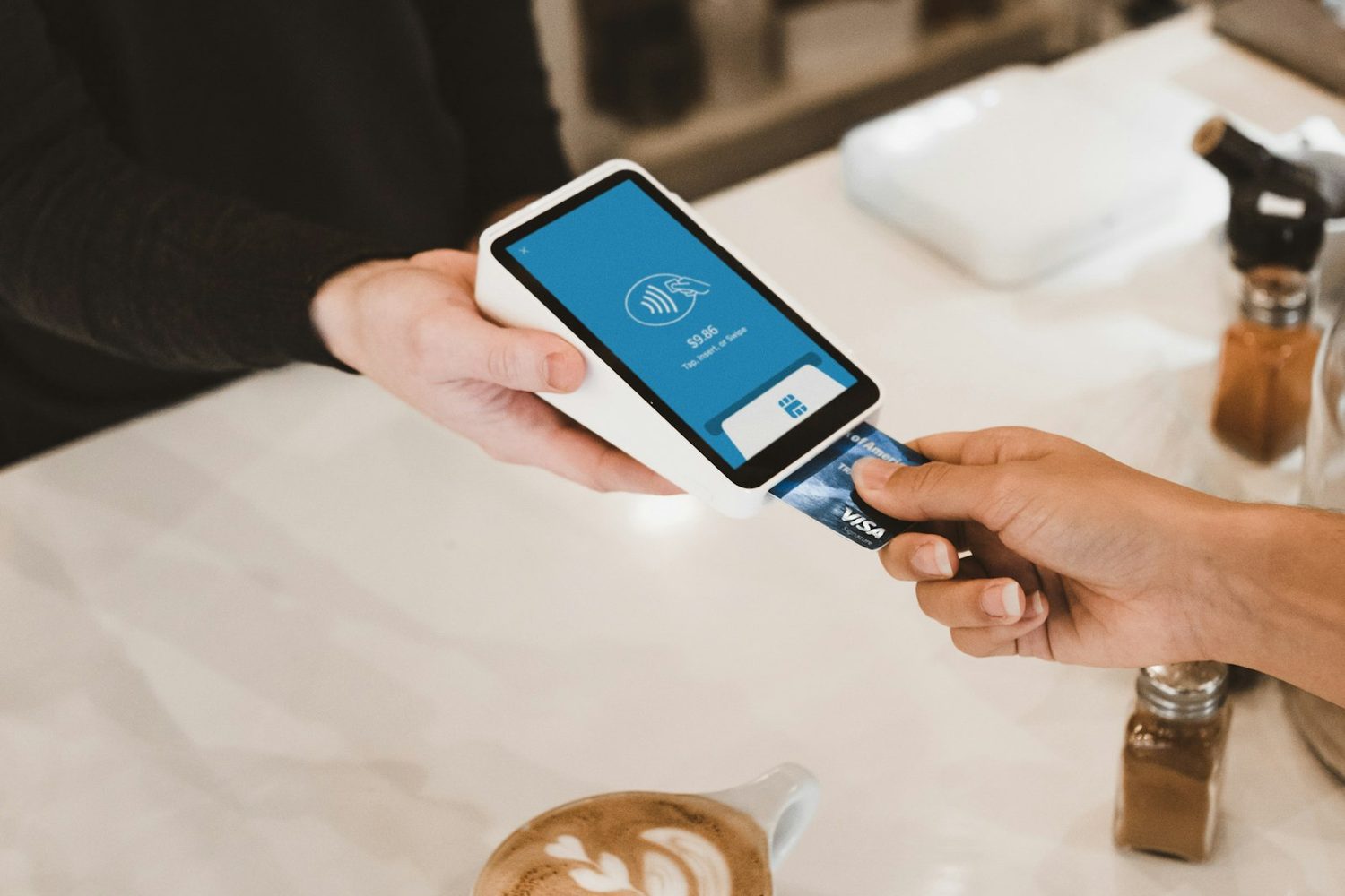 Customer inserting a Visa card into a payment terminal at a cafe counter