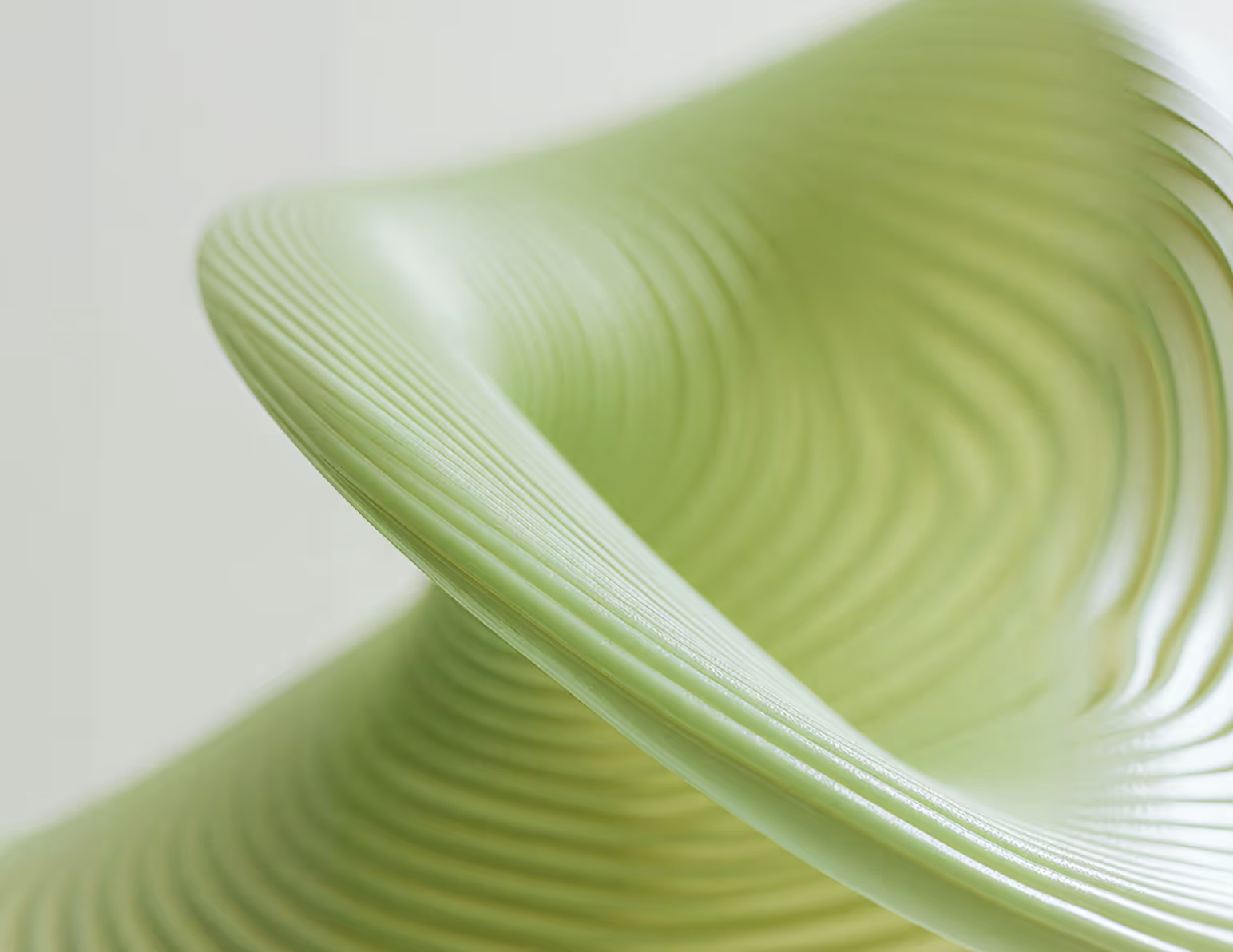 Close-up of a light green, ribbed, curved modern chair seat.