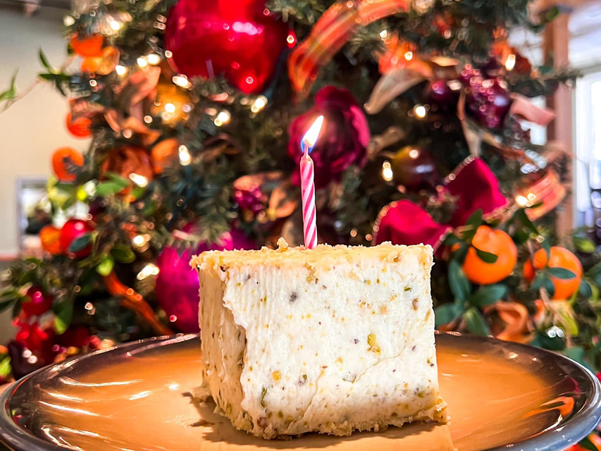 a slice of cake in front of a colorful Christmas tree