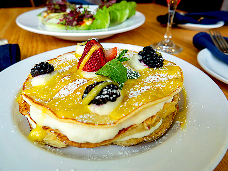 a plate of pancakes topped with berries and cream