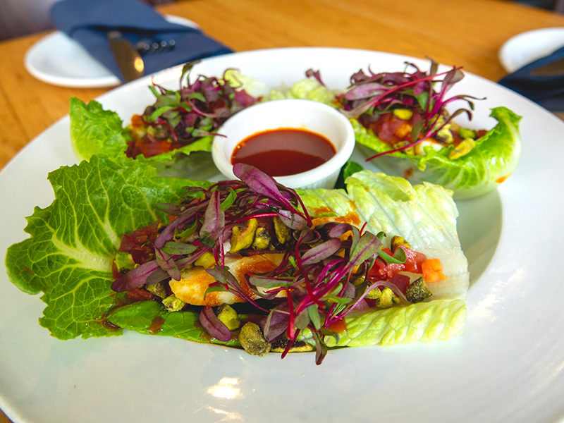 a plate of lettuce wrapped grilled halloumi, nuts, and greens