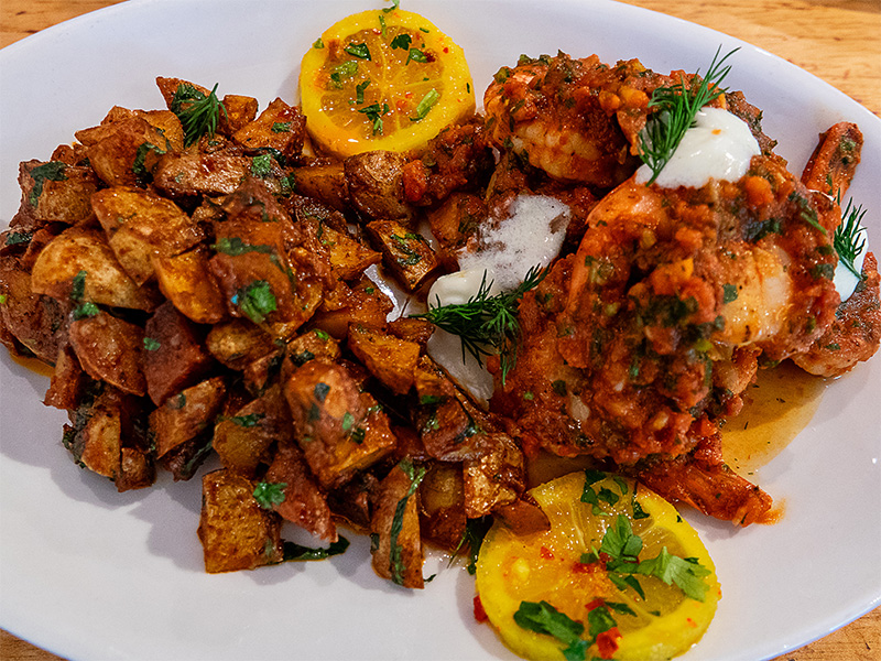 A plate of seared shrimp with sun-dried tomato relish and roasted potatoes