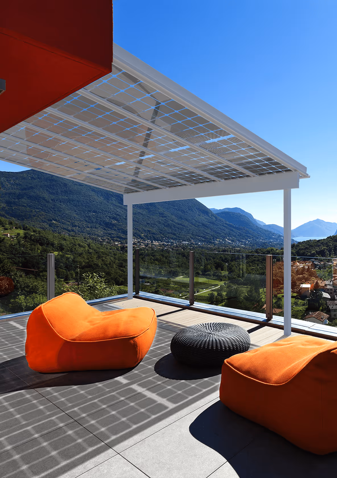 Moderne Terrasse mit orangenen Lounge-Sesseln, Solardach, Bergblick und klarem Himmel.