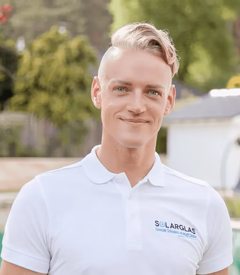 Mann mit weißem Poloshirt und Solarglas-Logo, lächelt im Freien, grüner Hintergrund.
