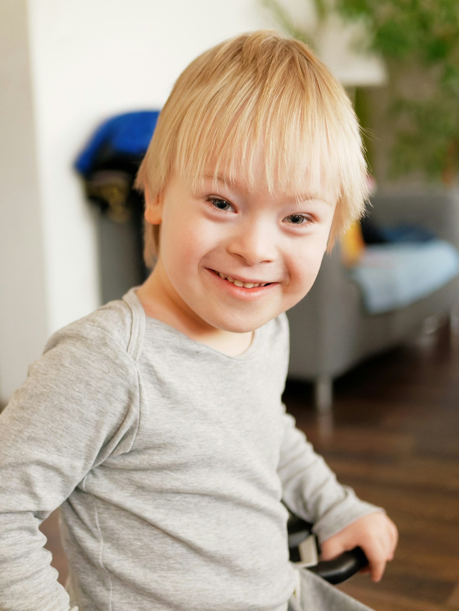 A smiling young boy with blond hair at home.