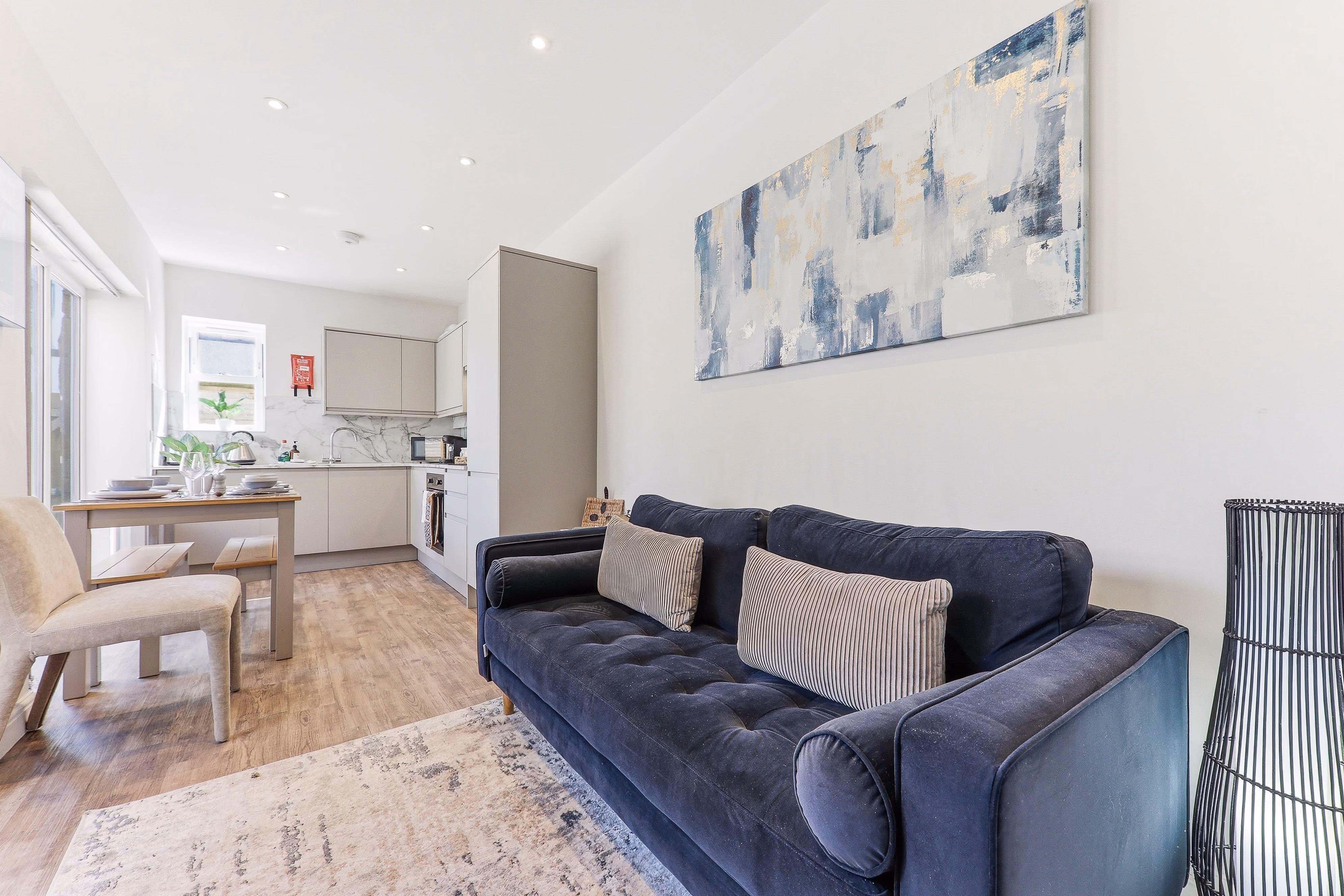 Open-plan living room with a navy sofa in a Mayfield Grove serviced apartment, Harrogate