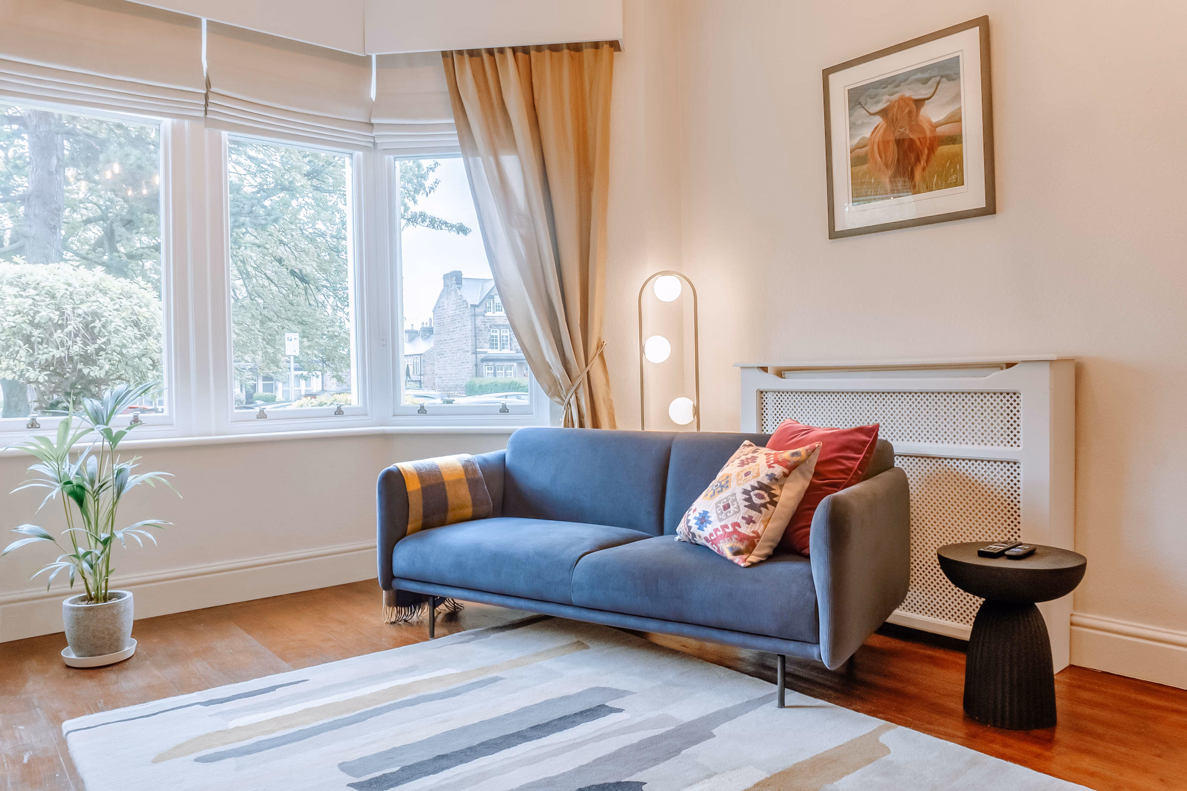 Living room with a blue sofa and bay window at The Harrogate Townhouse
